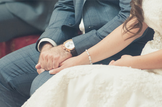 wedding couple holding hands during the wedding ceremony with watch and bracelet shown