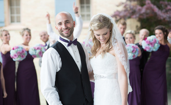 smiling couple posing wedding party in background
