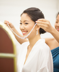 asian bride putting on necklace