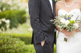 bride and groom together outside while bride holds green and purple bouquet