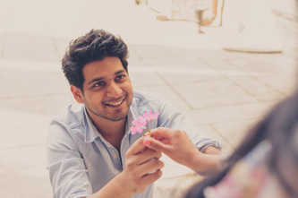 groom on knees giving flower