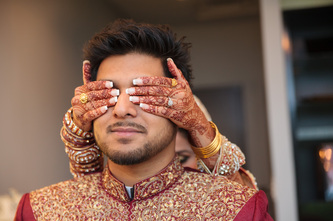 bride with henna on her hands holding the eyes of her groom