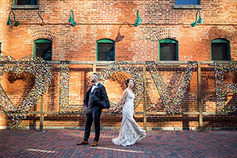 bride and groom posing in front of the love sign at distillery district in Toronto