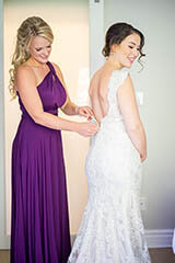 maid of honour helping the bride put on the wedding dress