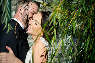 close up of bride and groom hugging in the middle of willow trees