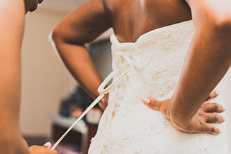 bride putting on her dress and tying the back of the dress
