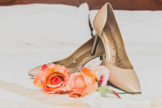 bright pick roses next to the beige wedding shoes