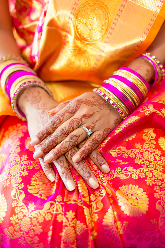 close up of indian bride's hands ring and red and pink wedding dress