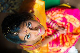 close up of bride sitting looking up and smiling while wearing pink and yellow wedding dress